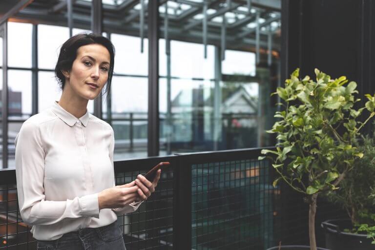 Vrouw met telefoon in kantoorgebouw